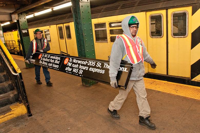 A group of workers carrying a box
Description automatically generated